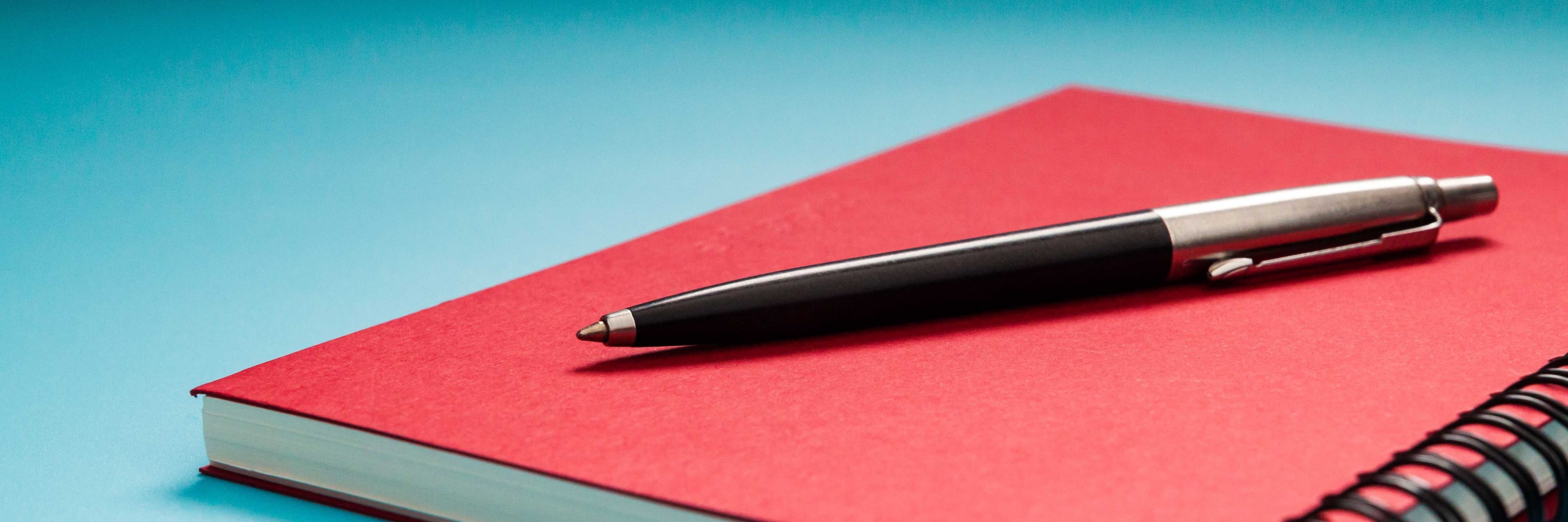 Stift auf rotem Notizbuch Stift auf rotem Notizbuch