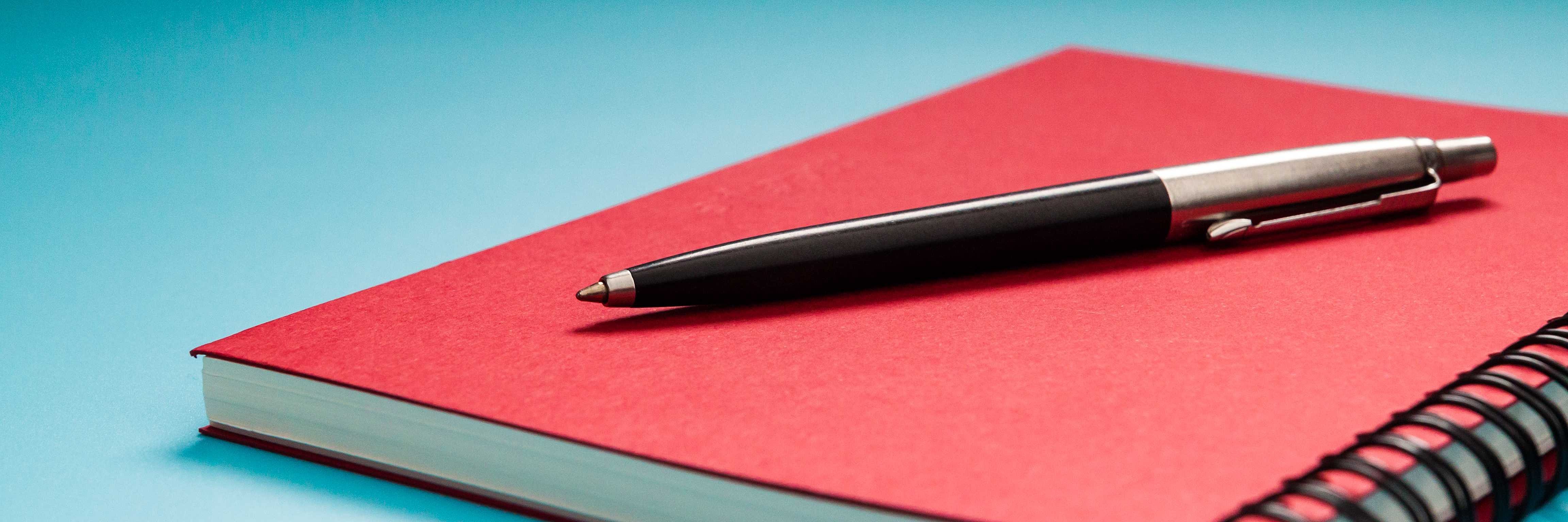Stift auf rotem Notizbuch Stift auf rotem Notizbuch