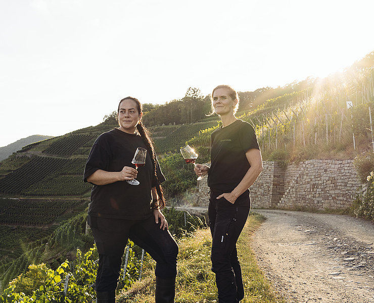 Weinprobe im Weingut Meyer-Näkel in Dernau mit Ausblick auf die terrassierten Weinberge und Sonnenuntergang.